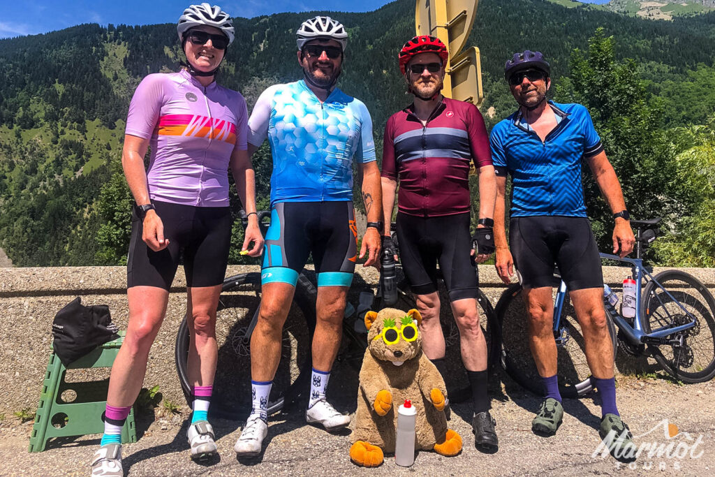 Group of cyclists posing for photo with Marmot Tours mascot on French Alps cycling holiday