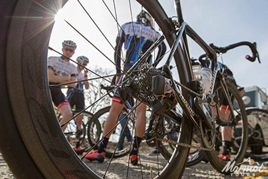 Group of cyclists seen through spokes of carbon wheel on Marmot Tours supported road cycling holidays in Europe