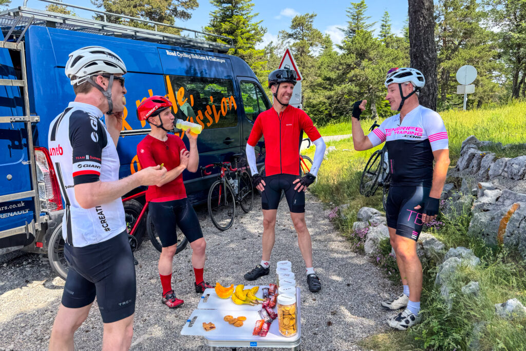 Group of cyclists enjoying snacks and drinks from Marmot Tours support vehicle