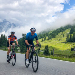 Cyclists riding mountain climb with mountains backdrop on Marmot Tours guided cycling holiday Italian Dolomites