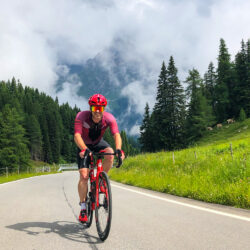 Cyclist riding mountain climb with mountains backdrop on Marmot Tours guided cycling holiday Italian Dolomites