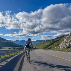 Cyclist climbing mountain pass with mountains backdrop on Marmot Tours guided road cycling holiday Italian Dolomites