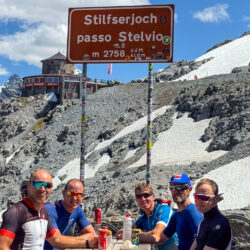 Group of cyclists enjoying rest stop and drinks at summit of Passo hello Stelvio on Marmot Tours guided road cycling holiday