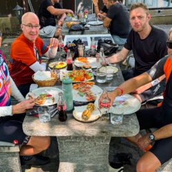 Group of cyclists enjoying lunch at cafe on Marmot Tours guided road cycling holiday Italian Dolomites Swiss Alps