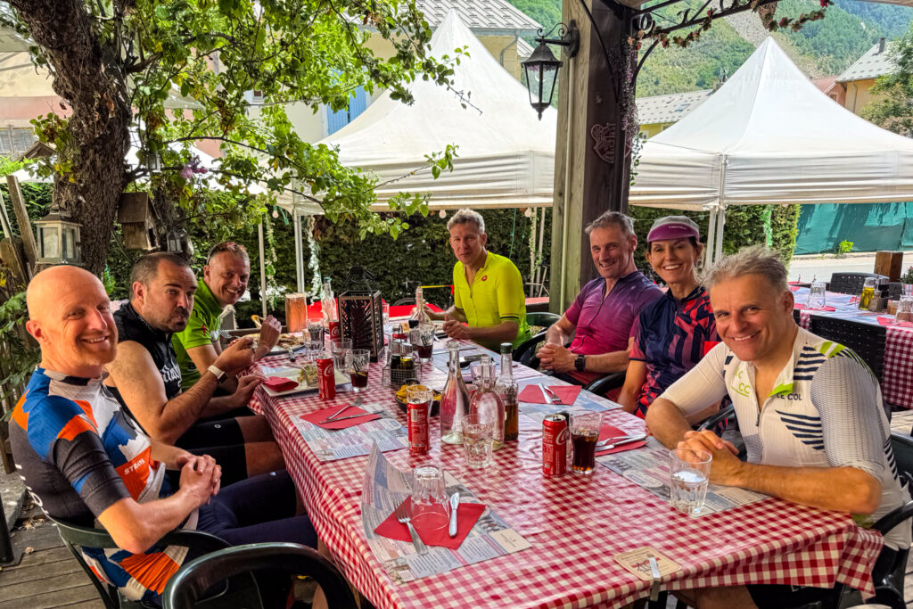 Group of cyclists enjoy lunch under shade in cafe on Marmot Tours guided road cycling holiday