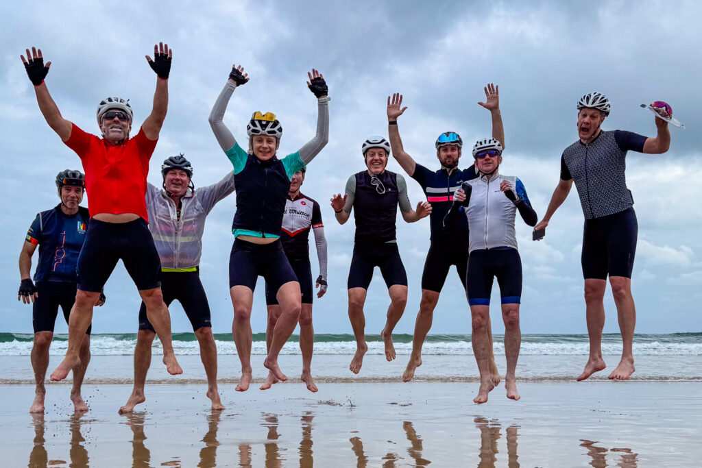 Group of cyclists jumping on beach at Hendaye on Raid Pyrenees cycling challenge with Marmot Tours