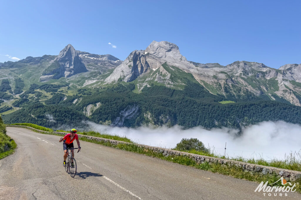 Cyclist climbing Col d'Aubisque with mountain peaks backdrop on Marmot Tours Raid Pyrenees