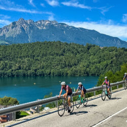 group of cyclists riding alongside lago di levico on marmot tours guided road cycling holiday Monte grappa dolomites