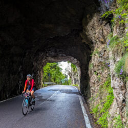 cyclist riding through tunnel on monte grappa from semonzo climb with marmot tours guided road cycling holiday in dolomites