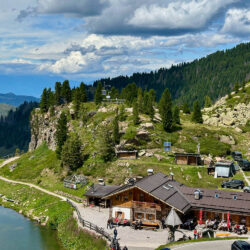 view of cafe and lake on passo manghen climb with forest backdrop on marmot tours guided road cycling tour monte grappa southern dolomites