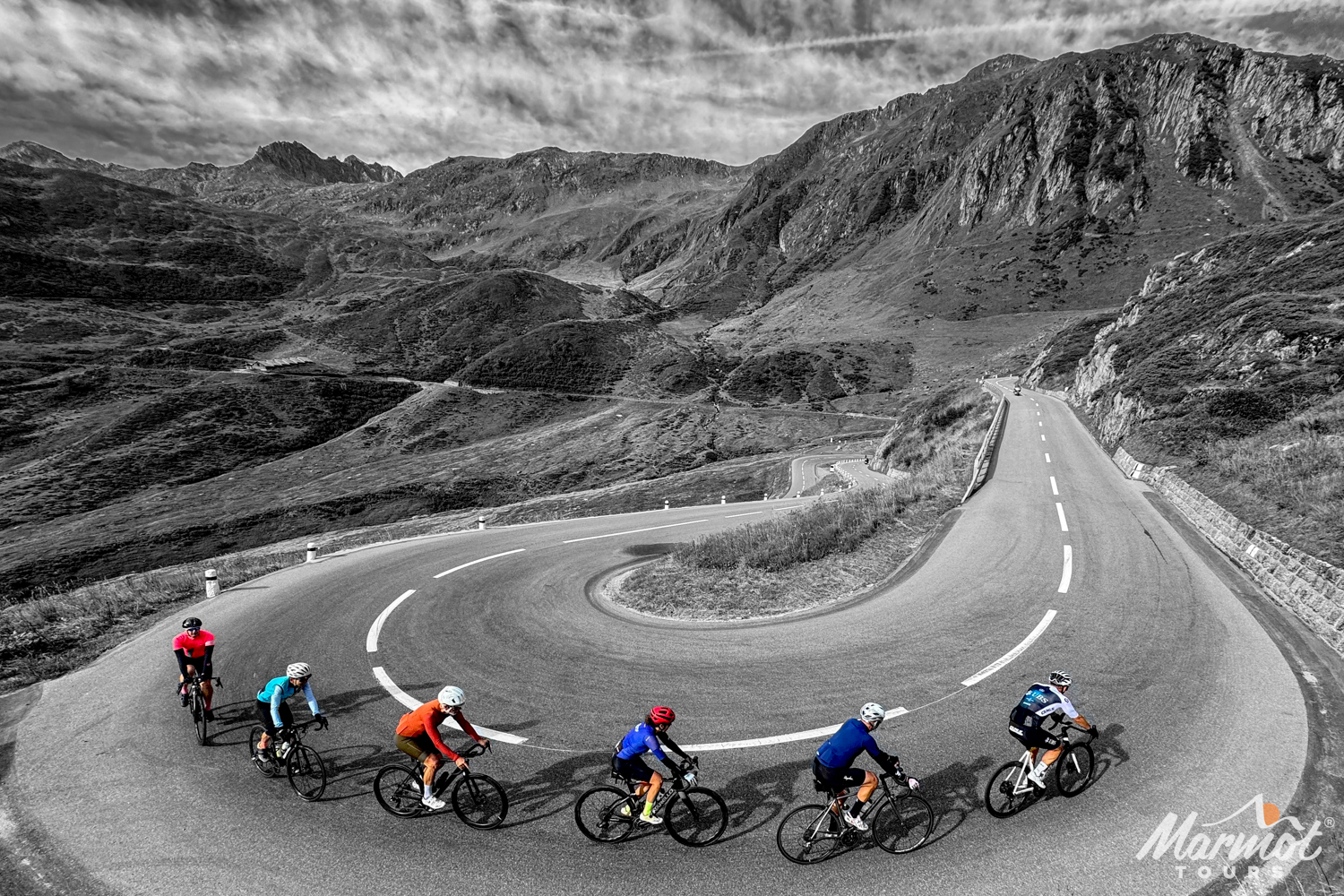 Black and white image with group of cyclists in coloured jerseys rounding hairpin bend on cycling holiday Swiss alps with marmot tours