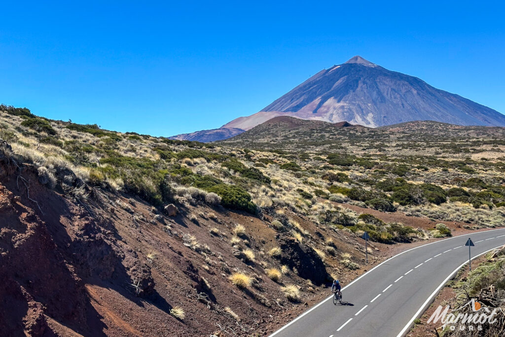 Cyclist on long straight road with towering Mount Teide in background on guided road cycling tour Tenerife with Marmot Tours