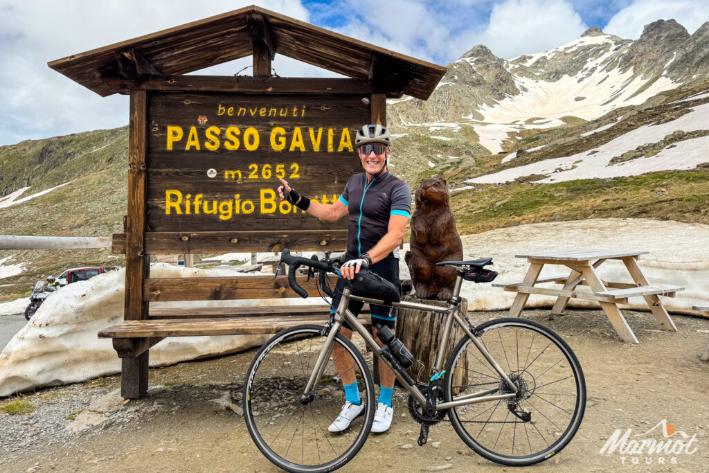 Cyclists pointing at Passo di Gavia sign with Marmot Tours hire bike