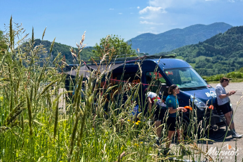 Group of cyclists enjoying rest stop at support vehicle on sunny day on cycling holiday in French Pyrenees foothills with Marmot Tours