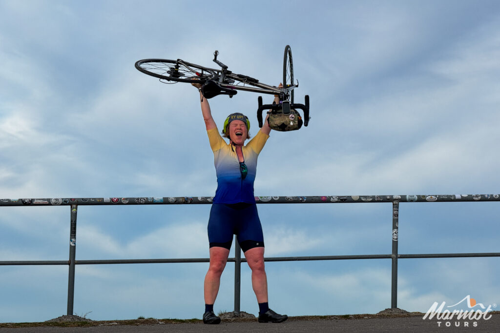 Female cyclist holding bike aloft on Alto Gamoniteiro on Marmot Tours guided cycling holiday asturias picos northern Spain