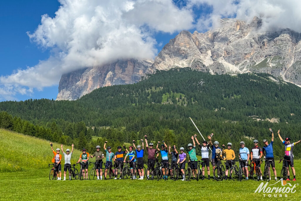 Group of cyclists post with Dolomites mountains backdrop on Marmot Tours guided road cycling holiday